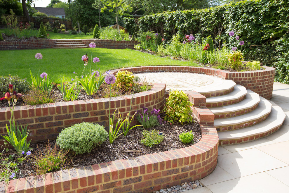 Large traditional sloped full sun formal garden in Cheshire with brick pavers.