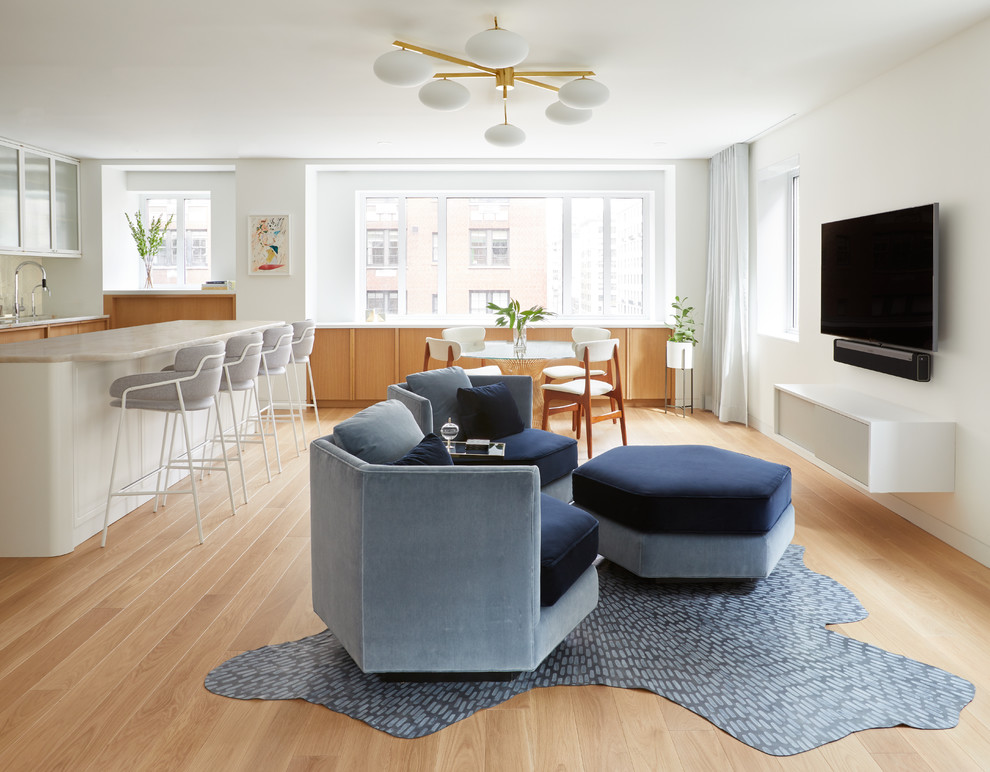 Photo of a contemporary open concept living room in New York with white walls, light hardwood floors, no fireplace, a wall-mounted tv and beige floor.