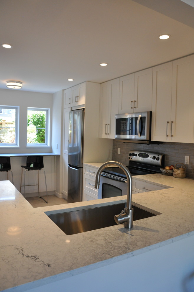 Small transitional u-shaped vinyl floor and beige floor eat-in kitchen photo in Vancouver with a single-bowl sink, shaker cabinets, white cabinets, quartz countertops, gray backsplash, ceramic backsplash, stainless steel appliances, no island and gray countertops