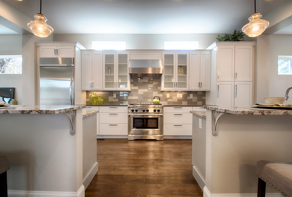 This is an example of a large modern l-shaped eat-in kitchen in Denver with shaker cabinets, white cabinets, stainless steel appliances, medium hardwood floors and multiple islands.