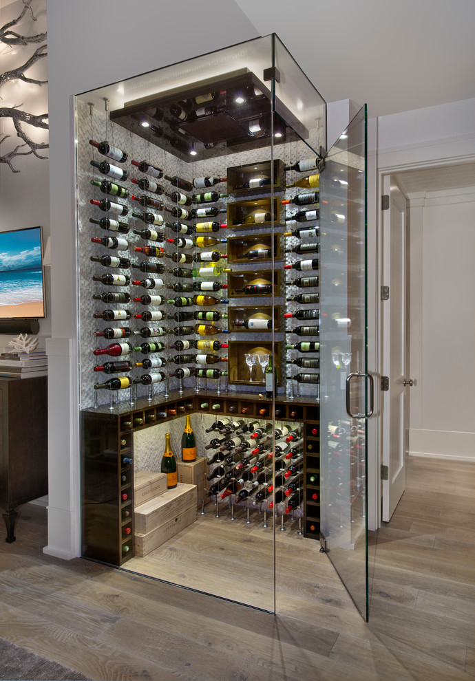This is an example of a beach style wine cellar in Miami with storage racks and light hardwood floors.