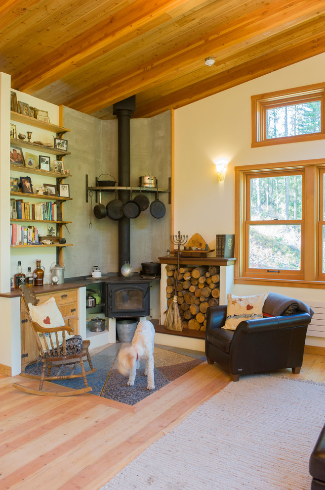 Photo of a country living room in Seattle with beige walls, light hardwood floors and a wood stove.