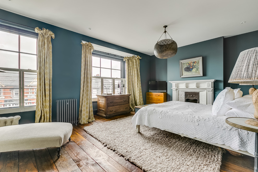 Design ideas for a mid-sized traditional master bedroom in London with blue walls, medium hardwood floors and brown floor.
