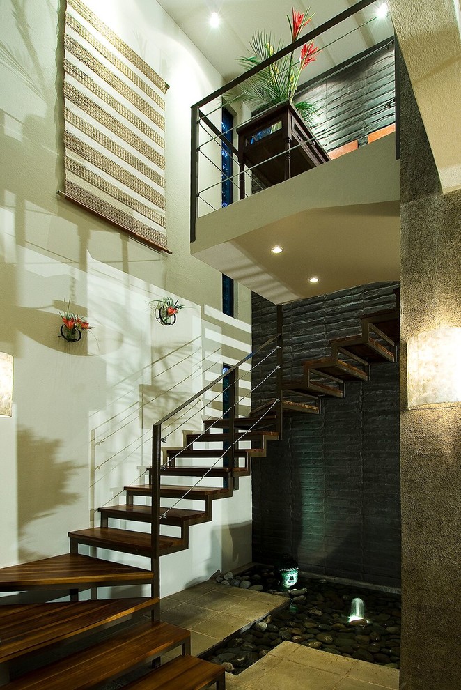 This is an example of a large tropical wood u-shaped staircase in San Luis Obispo with open risers and metal railing.