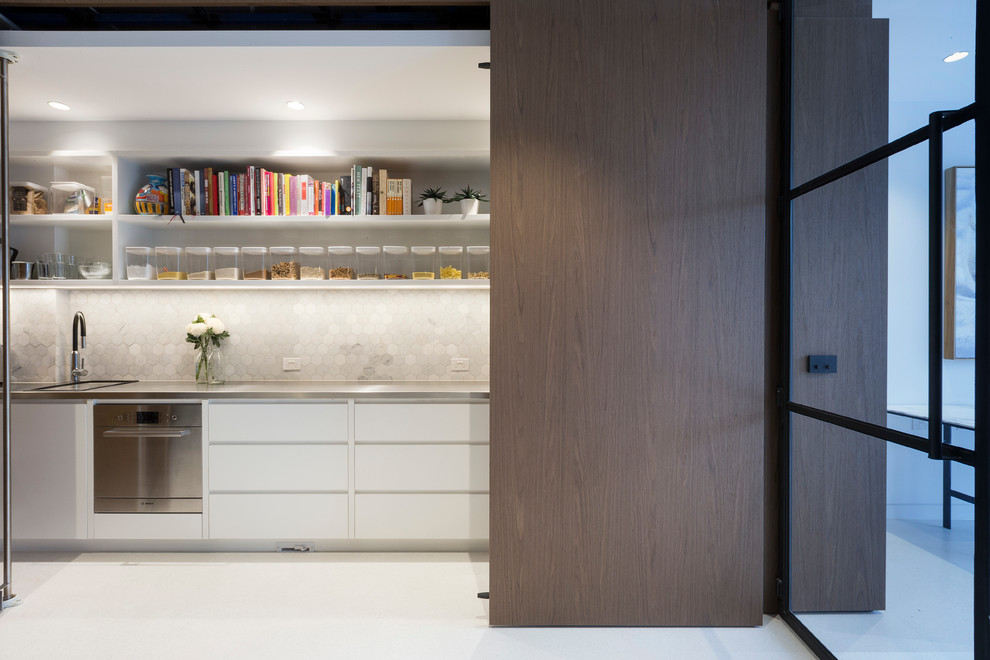 Contemporary single-wall kitchen in Melbourne with flat-panel cabinets, white cabinets and grey splashback.