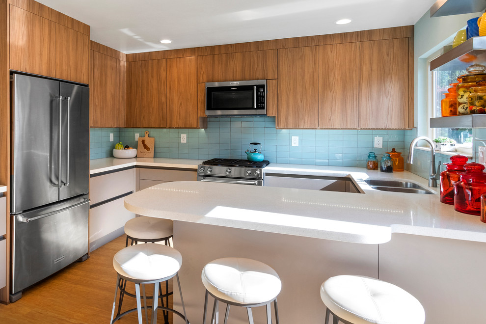 Design ideas for a midcentury kitchen in Other with an undermount sink, flat-panel cabinets, quartz benchtops, blue splashback, subway tile splashback, stainless steel appliances, vinyl floors and white benchtop.