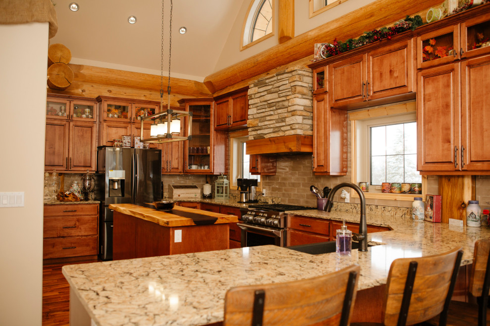 Inspiration for a mid-sized country u-shaped eat-in kitchen in Vancouver with a farmhouse sink, recessed-panel cabinets, medium wood cabinets, granite benchtops, beige splashback, stainless steel appliances, medium hardwood floors, with island, brown floor and beige benchtop.