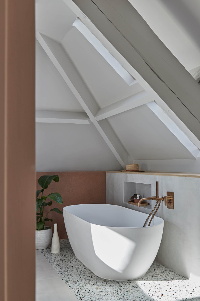 На фото: большая ванная комната в скандинавском стиле с накладной ванной, серыми стенами и полом из терраццо с