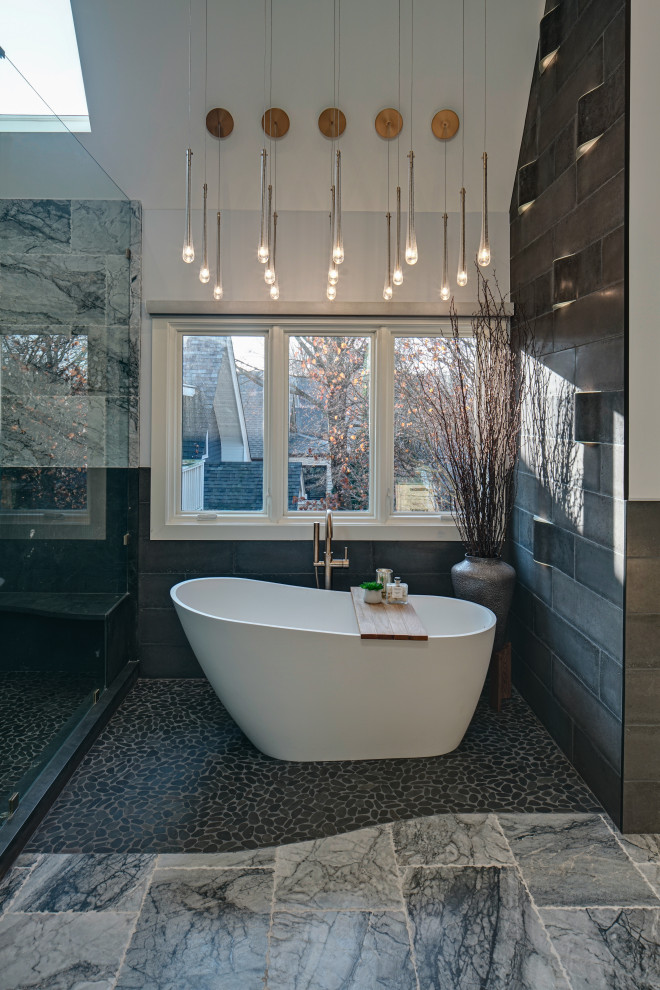 Inspiration for a large modern master bathroom in Chicago with flat-panel cabinets, beige cabinets, a freestanding tub, a corner shower, a one-piece toilet, cement tile, grey walls, marble floors, an undermount sink, quartzite benchtops, grey floor, a hinged shower door, black benchtops, an enclosed toilet, a double vanity, a built-in vanity and vaulted.