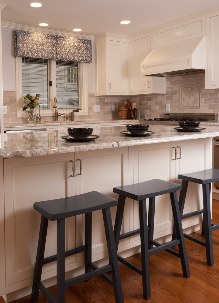 Inspiration for a mid-sized transitional l-shaped medium tone wood floor and brown floor enclosed kitchen remodel with an undermount sink, recessed-panel cabinets, white cabinets, quartz countertops, gray backsplash, stone tile backsplash, stainless steel appliances, an island and gray countertops