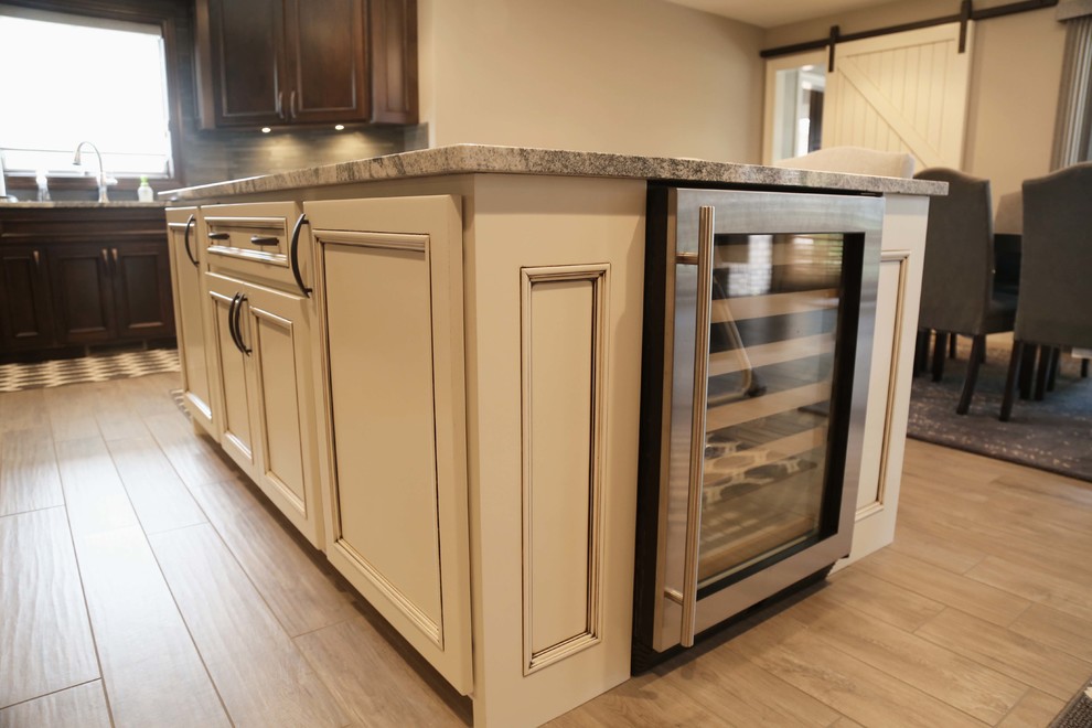 Inspiration for a mid-sized transitional l-shaped porcelain tile eat-in kitchen remodel with an undermount sink, raised-panel cabinets, dark wood cabinets, granite countertops, gray backsplash, porcelain backsplash, stainless steel appliances and an island