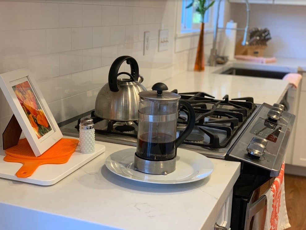 Eat-in kitchen - mid-sized rustic brown floor eat-in kitchen idea with a farmhouse sink, raised-panel cabinets, white cabinets, quartz countertops, white backsplash, stainless steel appliances, an island and white countertops