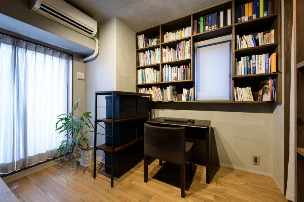 Inredning av ett asiatiskt hemmabibliotek, med grå väggar, ljust trägolv, ett inbyggt skrivbord och beiget golv
