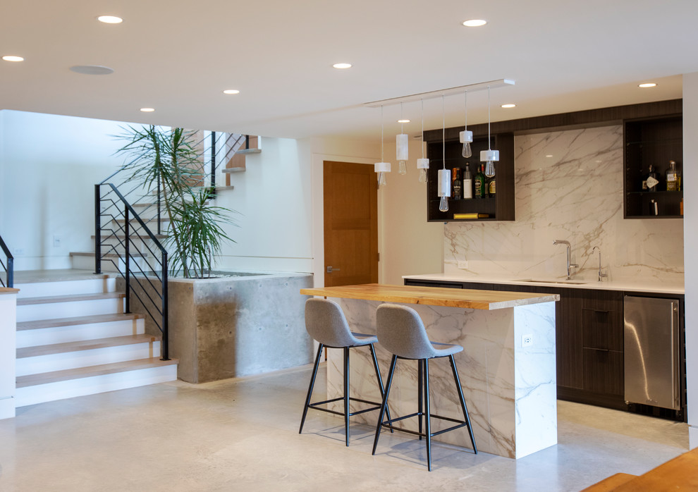 Mid-sized contemporary seated home bar in Vancouver with an undermount sink, flat-panel cabinets, black cabinets, wood benchtops, white splashback, marble splashback, concrete floors and grey floor.