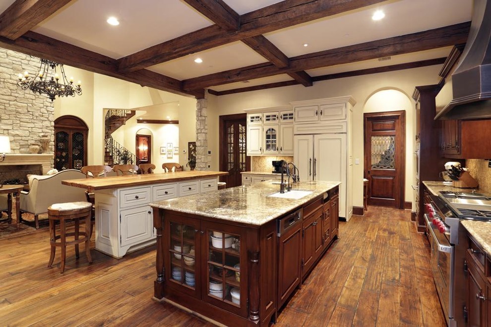 Photo of a large traditional l-shaped eat-in kitchen in Houston with a farmhouse sink, raised-panel cabinets, dark wood cabinets, wood benchtops, beige splashback, mosaic tile splashback, stainless steel appliances, medium hardwood floors and multiple islands.
