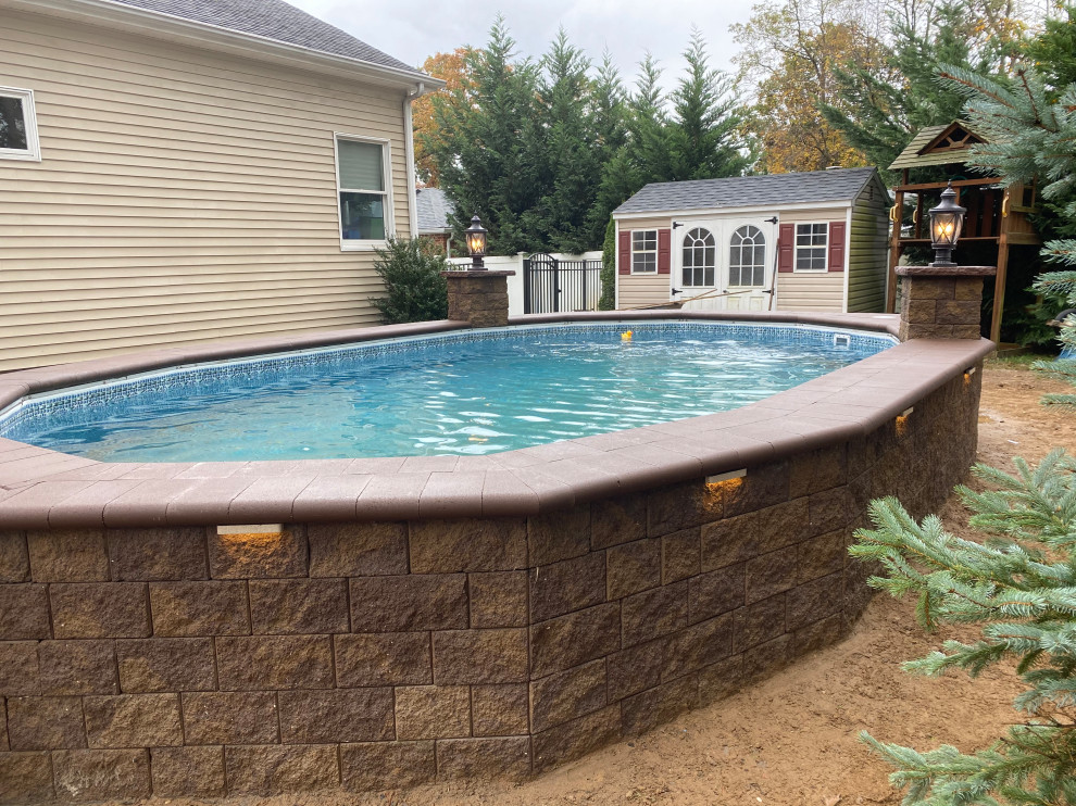This is an example of a large traditional back custom shaped above ground swimming pool in New York with with pool landscaping and concrete paving.
