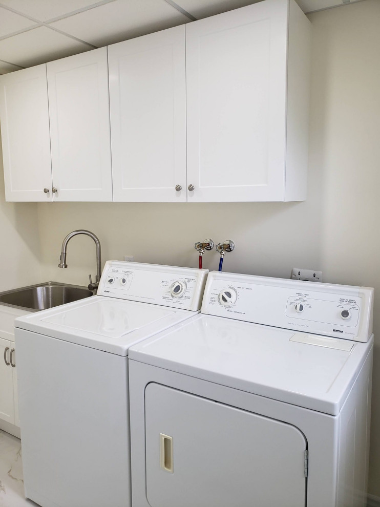 Inspiration for a transitional porcelain tile and white floor laundry room remodel with an utility sink, shaker cabinets, white cabinets, white walls and a side-by-side washer/dryer