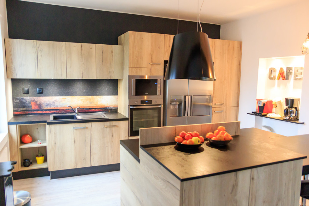 Inspiration for a mid-sized contemporary galley open plan kitchen in Nancy with a single-bowl sink, light wood cabinets, black splashback, stainless steel appliances, light hardwood floors, with island and brown floor.