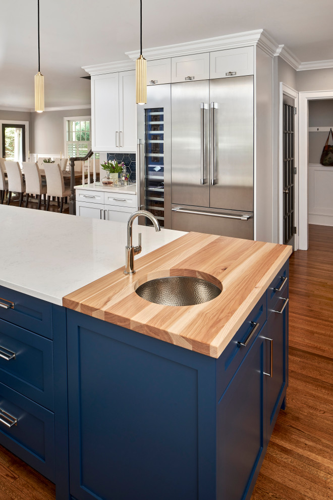 Inspiration for a large transitional l-shaped open plan kitchen in Charlotte with an undermount sink, shaker cabinets, blue cabinets, wood benchtops, blue splashback, ceramic splashback, stainless steel appliances, medium hardwood floors, with island, brown floor and brown benchtop.