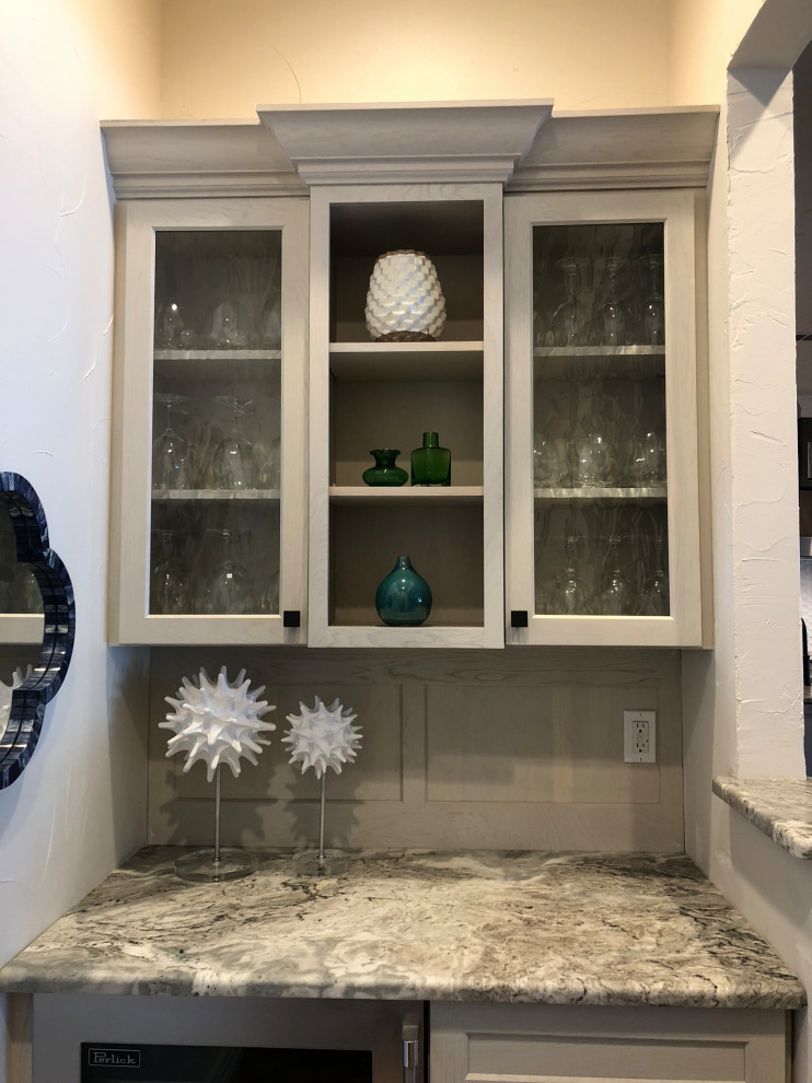 Photo of a small beach style single-wall home bar in Dallas with no sink, shaker cabinets, white cabinets, granite benchtops, white splashback, timber splashback, porcelain floors, brown floor and grey benchtop.