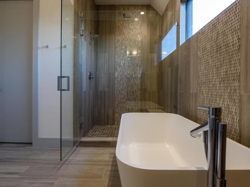 Large contemporary master bathroom in Austin with flat-panel cabinets, medium wood cabinets, a freestanding tub, a corner shower, gray tile, stone tile, grey walls, travertine floors, an undermount sink and engineered quartz benchtops.