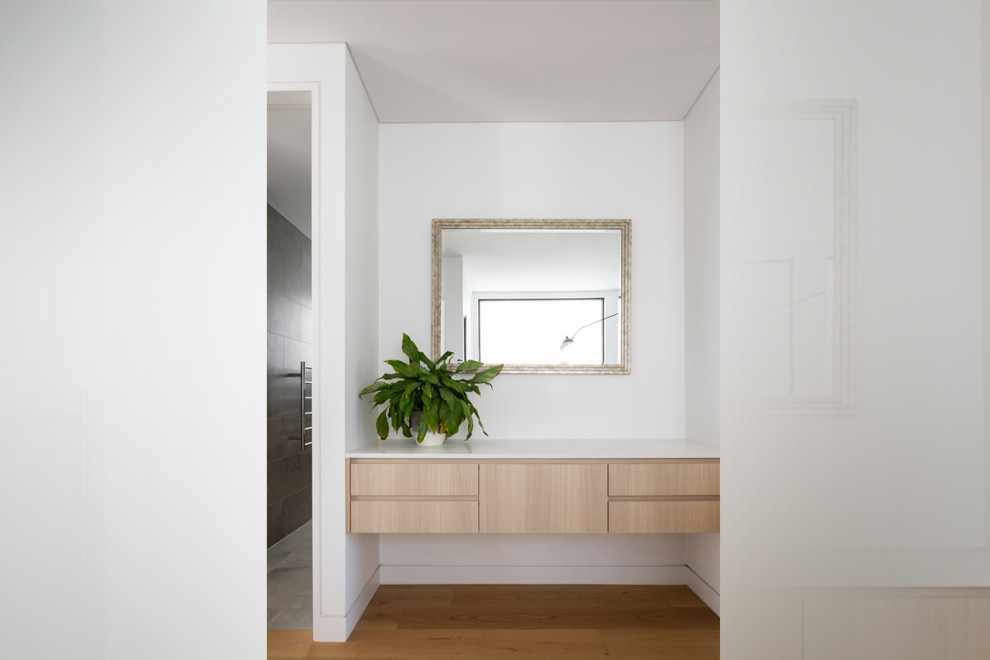This is an example of a large contemporary gender-neutral dressing room in Sydney with flat-panel cabinets, light wood cabinets, medium hardwood floors and brown floor.