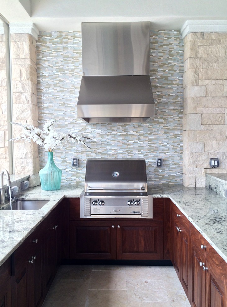 Inspiration for a large transitional u-shaped travertine floor home design remodel in Tampa with an undermount sink, raised-panel cabinets, medium tone wood cabinets, granite countertops, multicolored backsplash, glass tile backsplash and stainless steel appliances