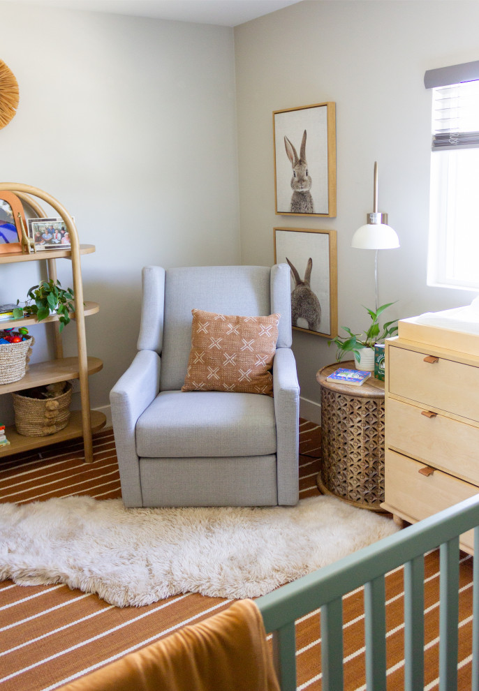 Ejemplo de habitación de bebé neutra actual pequeña con paredes blancas, moqueta y suelo naranja