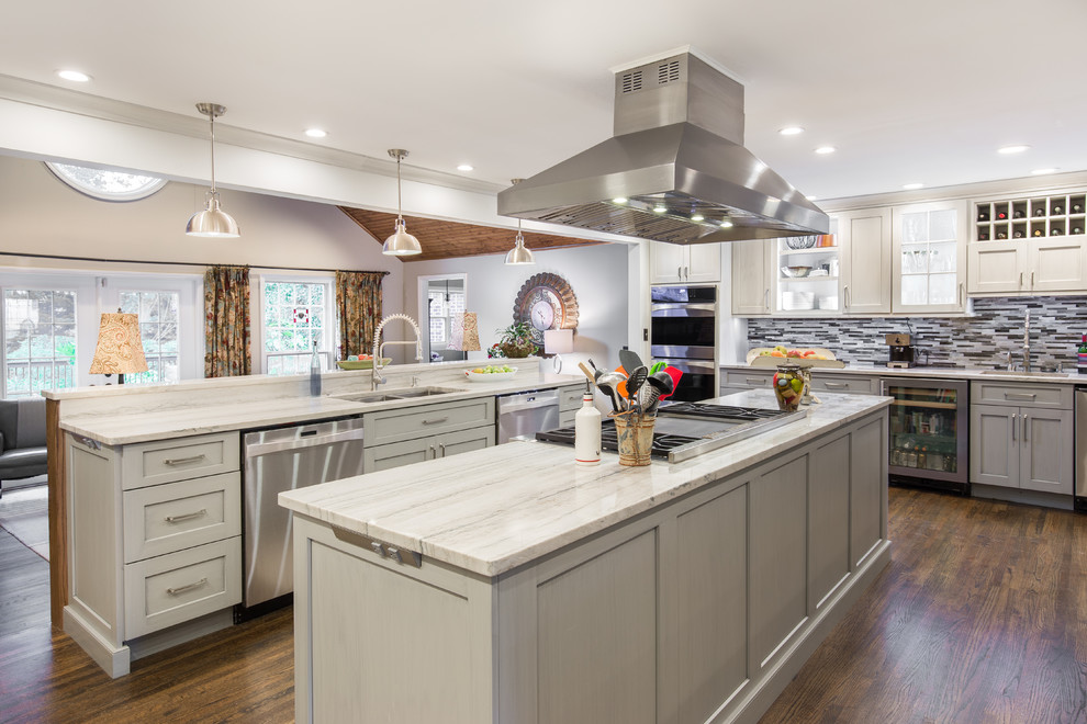 Large transitional single-wall medium tone wood floor and brown floor eat-in kitchen photo with an undermount sink, shaker cabinets, white cabinets, marble countertops, multicolored backsplash, matchstick tile backsplash, stainless steel appliances and two islands