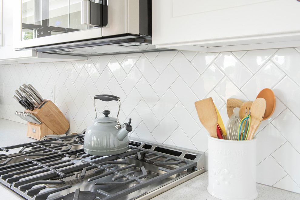 Inspiration for a mid-sized transitional l-shaped medium tone wood floor and brown floor open concept kitchen remodel with a farmhouse sink, shaker cabinets, white cabinets, quartzite countertops, white backsplash, subway tile backsplash, stainless steel appliances and an island