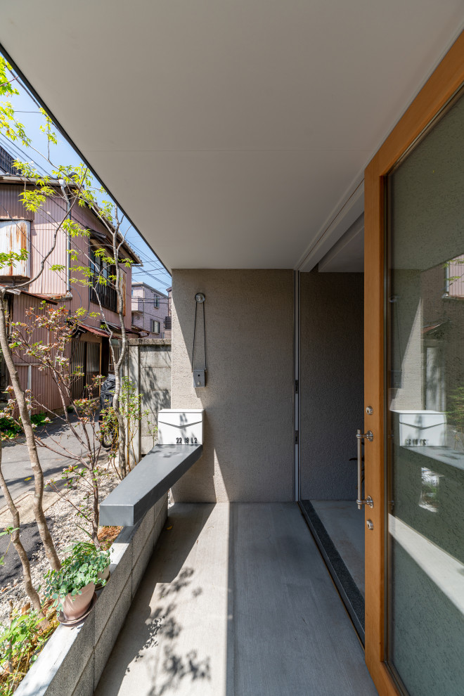 Cette photo montre un petit porche d'entrée de maison avant asiatique avec des pavés en béton et une extension de toiture.