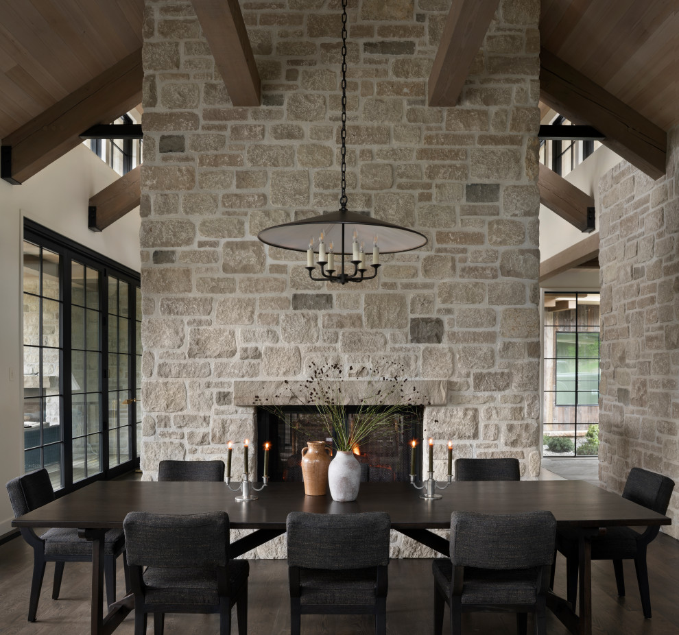 Example of a huge mountain style medium tone wood floor, brown floor and vaulted ceiling kitchen/dining room combo design in Los Angeles with white walls, a two-sided fireplace and a stone fireplace