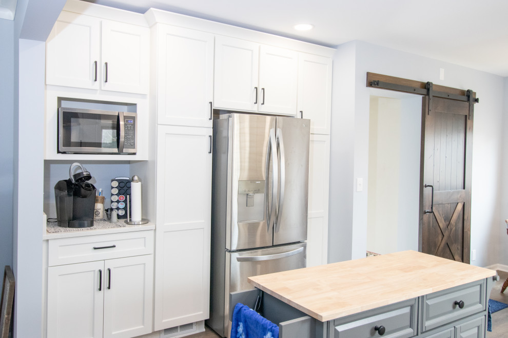 Example of a mid-sized transitional galley vinyl floor and brown floor eat-in kitchen design with an undermount sink, flat-panel cabinets, white cabinets, quartzite countertops, stainless steel appliances, an island and white countertops
