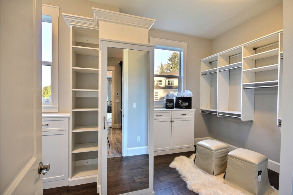 Photo of an expansive transitional gender-neutral walk-in wardrobe in Portland with recessed-panel cabinets, white cabinets and dark hardwood floors.