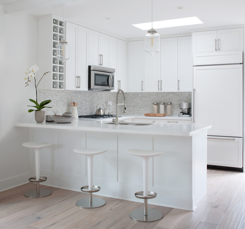 Contemporary u-shaped eat-in kitchen in Vancouver with a double-bowl sink, shaker cabinets, white cabinets, white splashback, panelled appliances, stone tile splashback and quartz benchtops.
