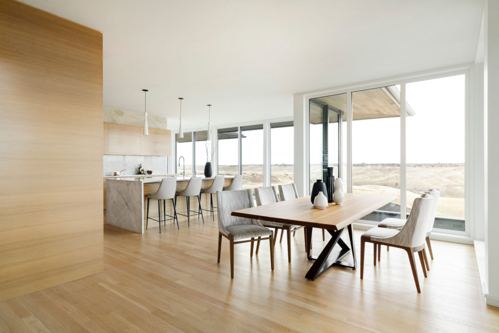 Immagine di una grande sala da pranzo aperta verso la cucina design con pareti bianche, parquet chiaro, pavimento beige e pareti in legno
