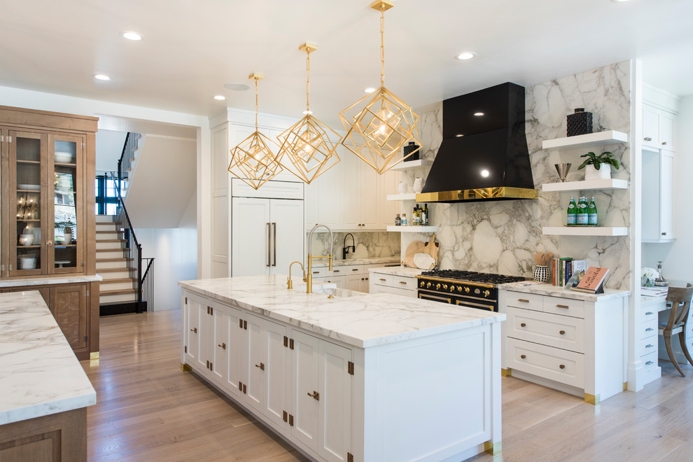 Design ideas for a large contemporary l-shaped eat-in kitchen in Salt Lake City with a farmhouse sink, shaker cabinets, white cabinets, marble benchtops, white splashback, marble splashback, panelled appliances, medium hardwood floors, multiple islands and brown floor.