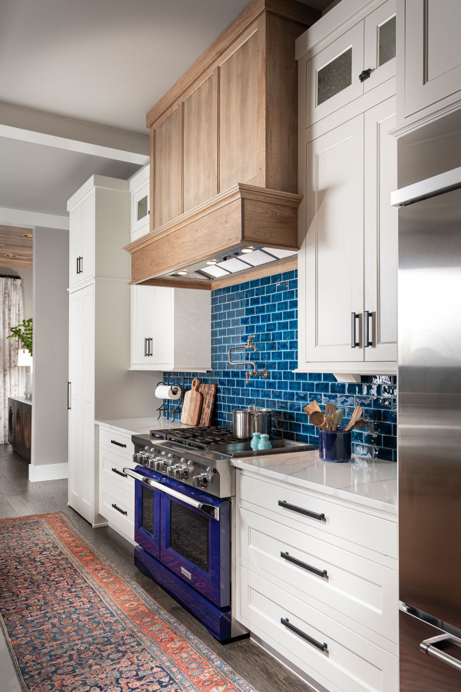 Example of a huge transitional u-shaped dark wood floor and brown floor eat-in kitchen design in Other with white cabinets, blue backsplash, subway tile backsplash, stainless steel appliances, an island, white countertops, quartz countertops and recessed-panel cabinets