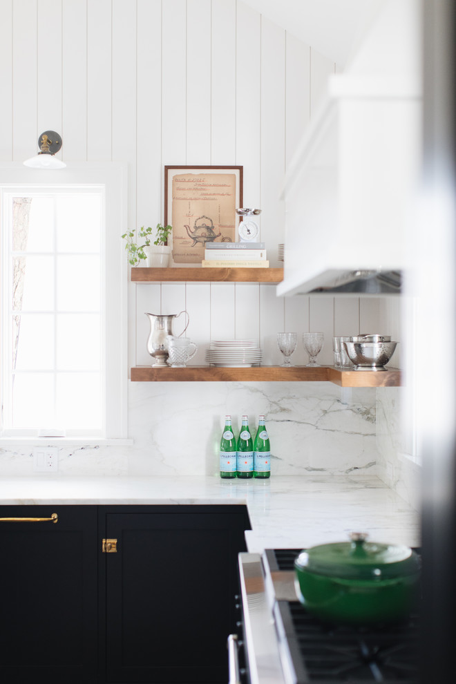 Example of a mid-sized transitional l-shaped medium tone wood floor and brown floor kitchen pantry design in Chicago with a farmhouse sink, shaker cabinets, black cabinets, marble countertops, white backsplash, marble backsplash, paneled appliances and an island