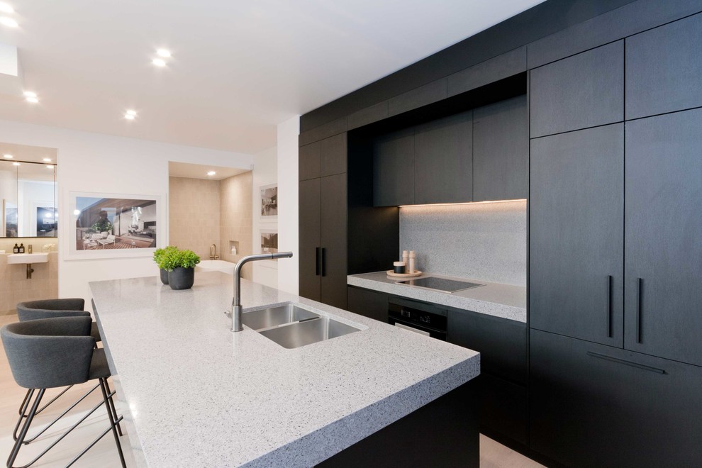 This is an example of a small contemporary galley eat-in kitchen in Sydney with an undermount sink, black cabinets, quartz benchtops, grey splashback, stone slab splashback, black appliances, porcelain floors, with island, beige floor and grey benchtop.