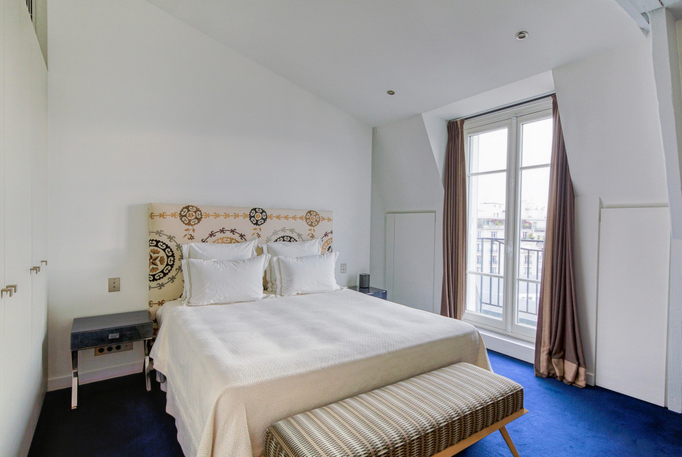 На фото: большая гостевая спальня (комната для гостей) в стиле модернизм с белыми стенами, ковровым покрытием, синим полом и балками на потолке без камина с