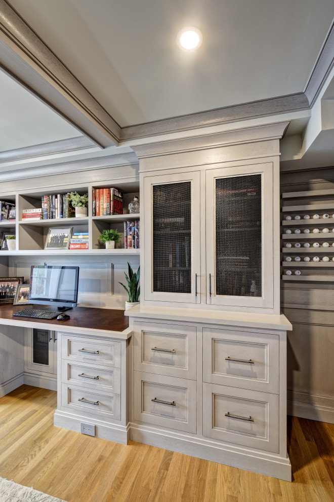 Diseño de despacho costero grande con paredes grises, suelo de madera clara, escritorio independiente, suelo marrón, casetón y panelado