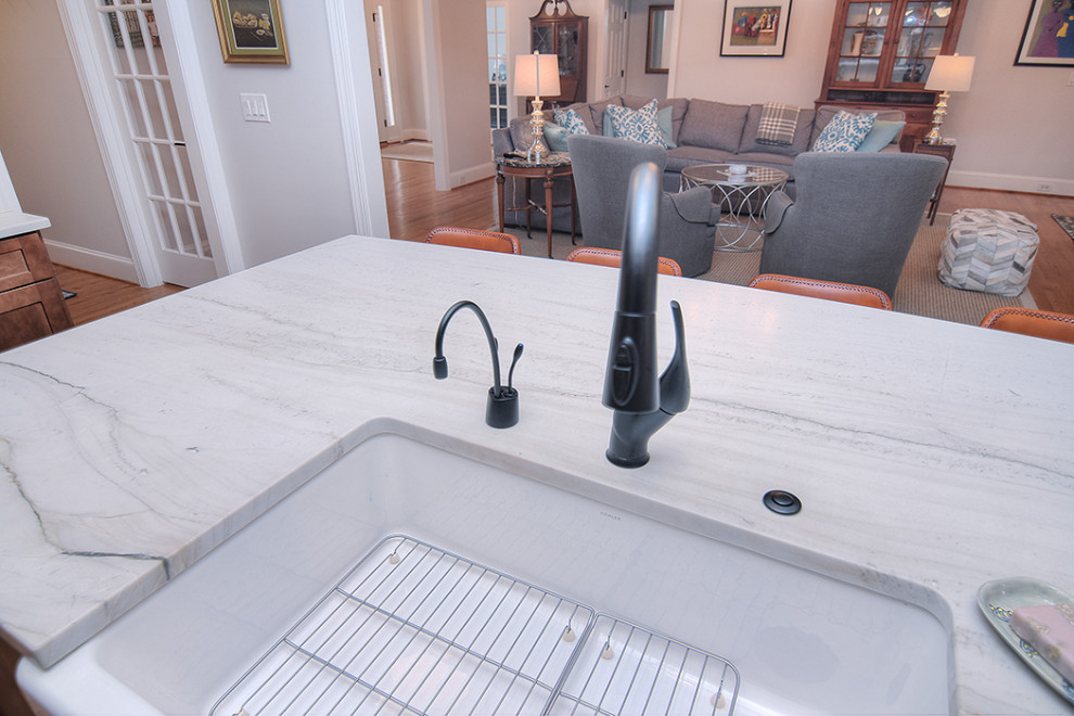 Example of a huge transitional light wood floor open concept kitchen design in Charlotte with a farmhouse sink, shaker cabinets, medium tone wood cabinets, quartzite countertops, an island and white countertops