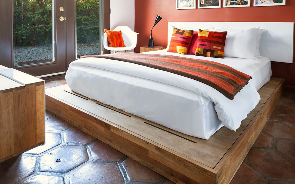 Design ideas for a mid-sized guest bedroom in Los Angeles with orange walls, terra-cotta floors and no fireplace.