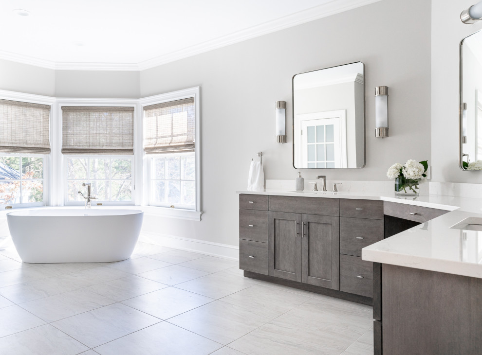 Inredning av ett klassiskt stort vit vitt en-suite badrum, med släta luckor, grå skåp, ett fristående badkar, grå väggar, klinkergolv i porslin, ett undermonterad handfat, bänkskiva i kvarts och grått golv