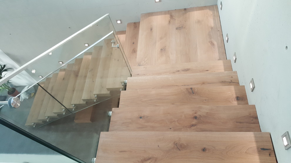 Design ideas for a large contemporary wood l-shaped staircase in Munich with glass railing.