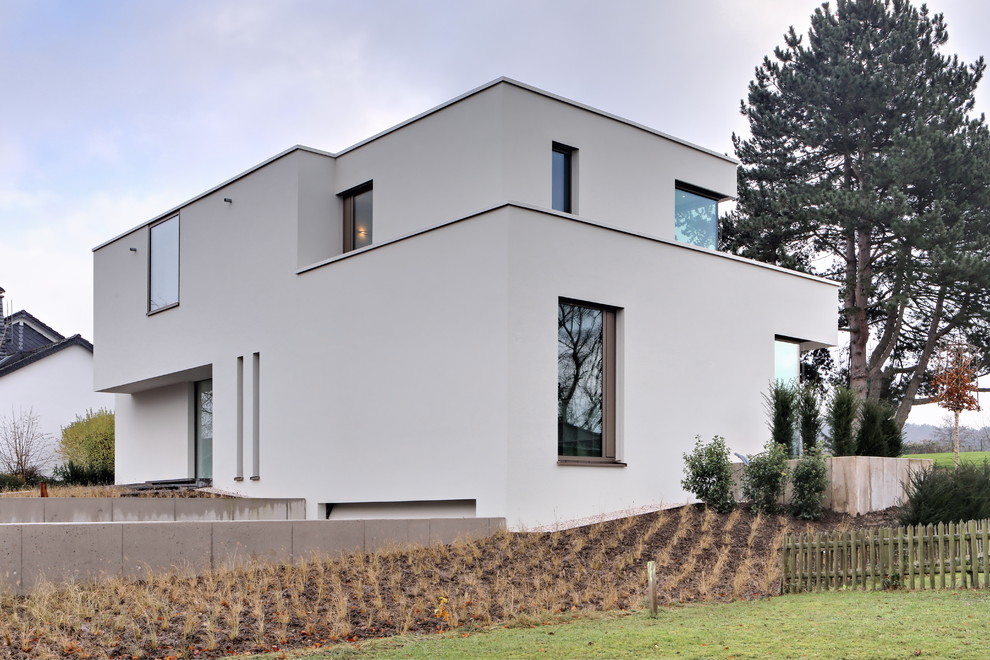 Mid-sized modern two-storey stucco beige house exterior in Bonn with a flat roof and a green roof.