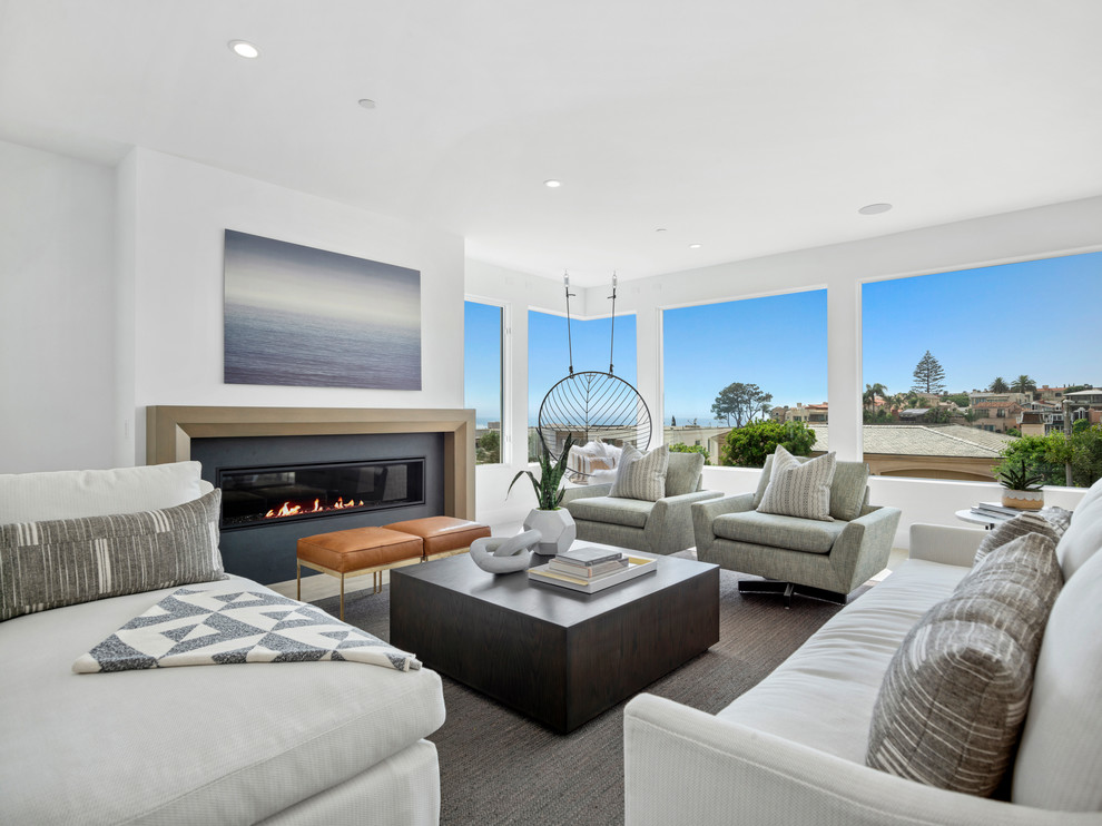 Photo of a beach style open concept living room in Orange County with white walls, a ribbon fireplace, a wall-mounted tv, grey floor, carpet and a stone fireplace surround.