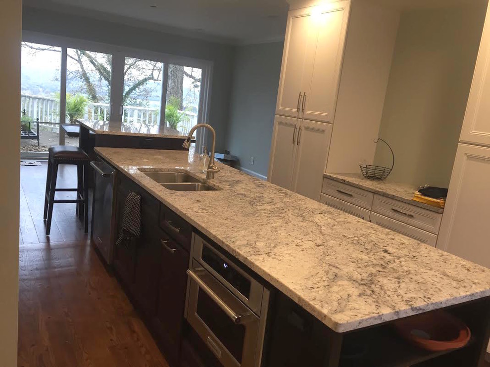 Inspiration for a mid-sized transitional galley dark wood floor eat-in kitchen remodel in Cincinnati with a double-bowl sink, recessed-panel cabinets, white cabinets, granite countertops, multicolored backsplash, matchstick tile backsplash, stainless steel appliances and an island