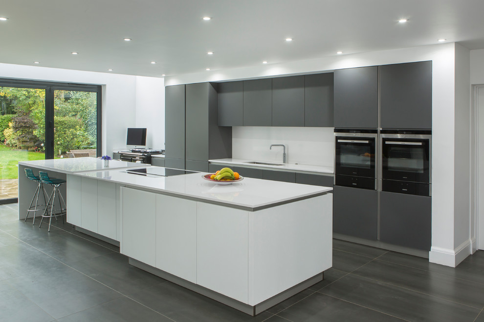 Photo of a large contemporary single-wall open plan kitchen in Essex with an integrated sink, flat-panel cabinets, grey cabinets, quartzite benchtops, white splashback, stone slab splashback, stainless steel appliances, porcelain floors and with island.